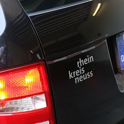 Ein Autoaufkleber mit dem Schriftzug "rhein kreis neuss"  in der Farbe silbergrau